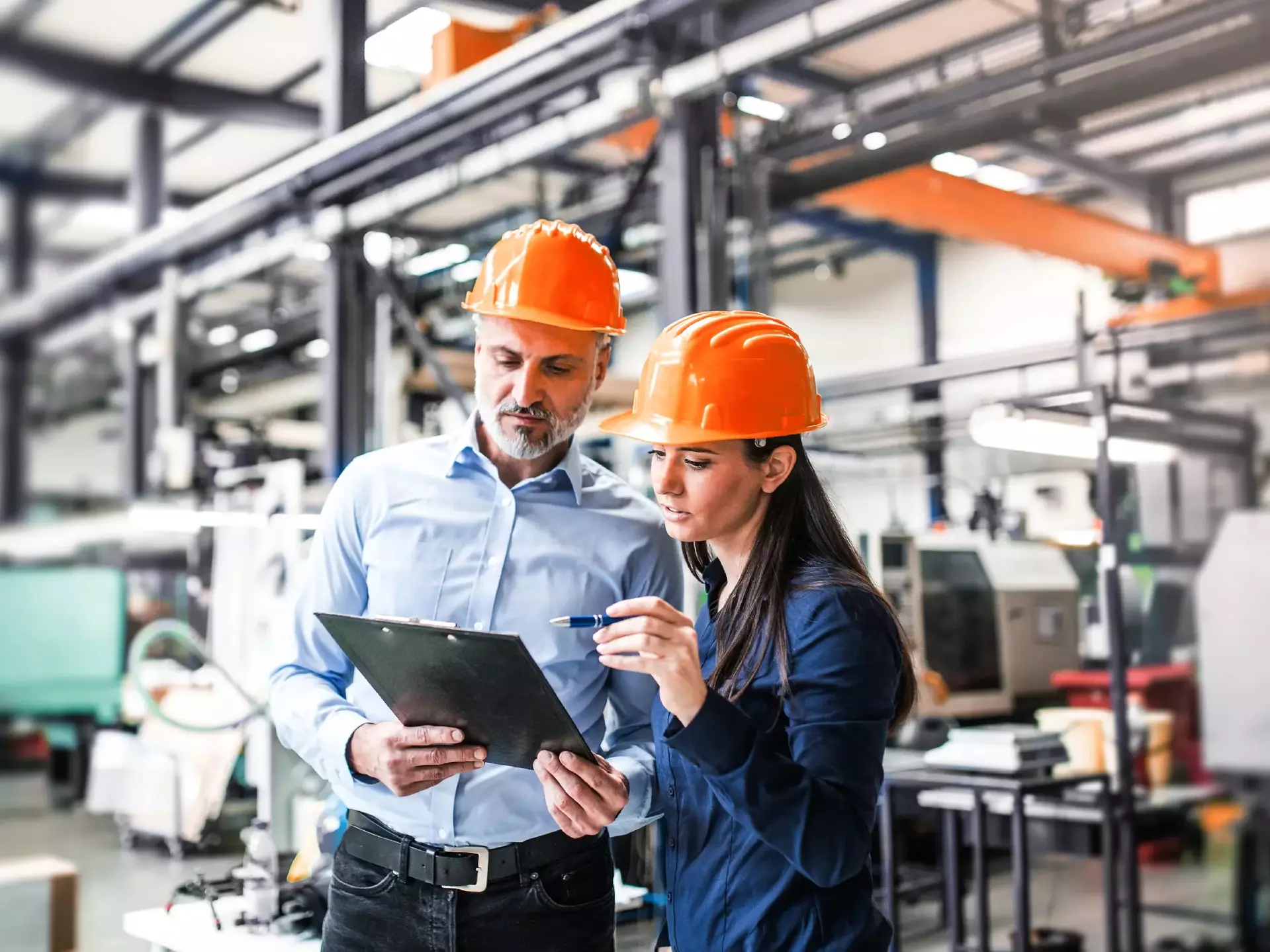 An industrial man and woman engineers in a factory checking documents