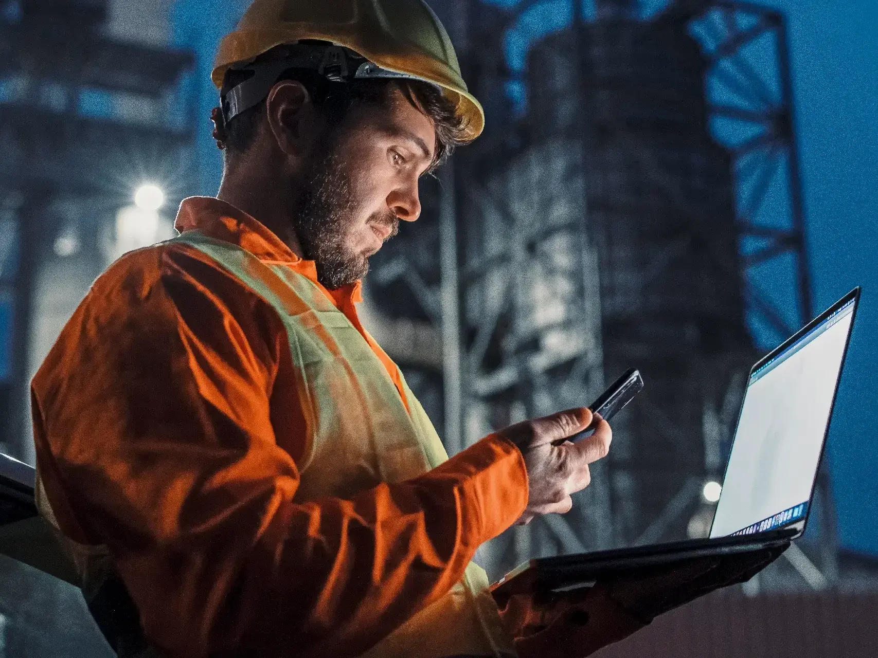Engineer working nightshift and using technology in front of petroleum industrial factory Engineer working nightshift and using technology in front of petroleum industrial factory