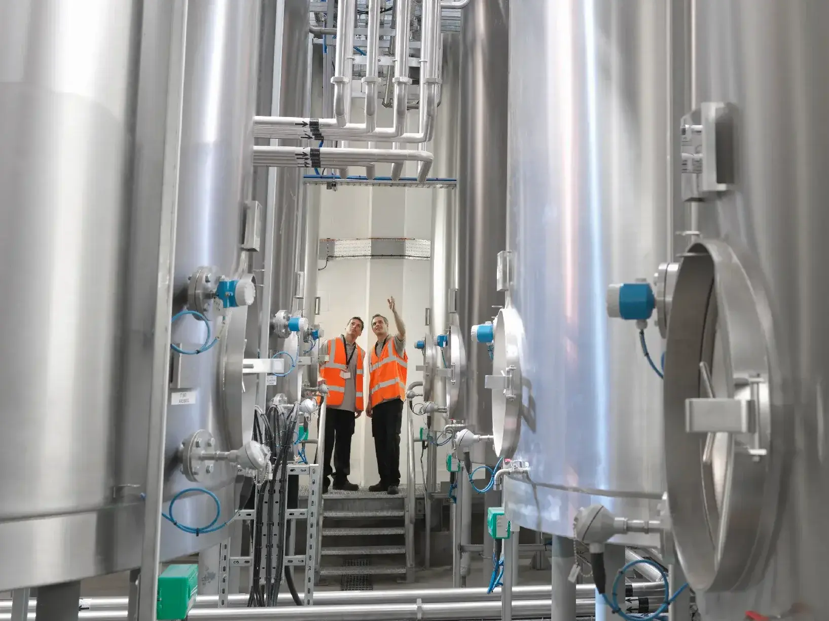 Factory workers examining storage tanks