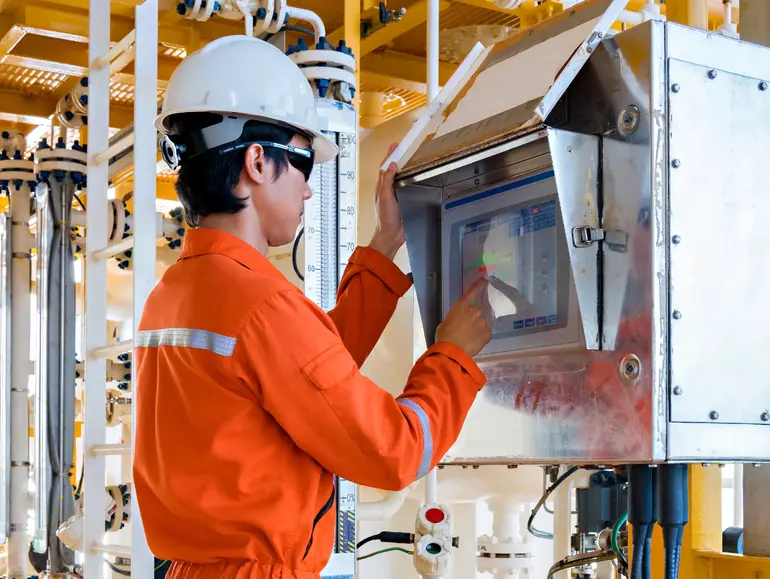 Offshore oil rig worker production operator operate valve by using touch screen panel to command open and close valve at oil and gas remote platform