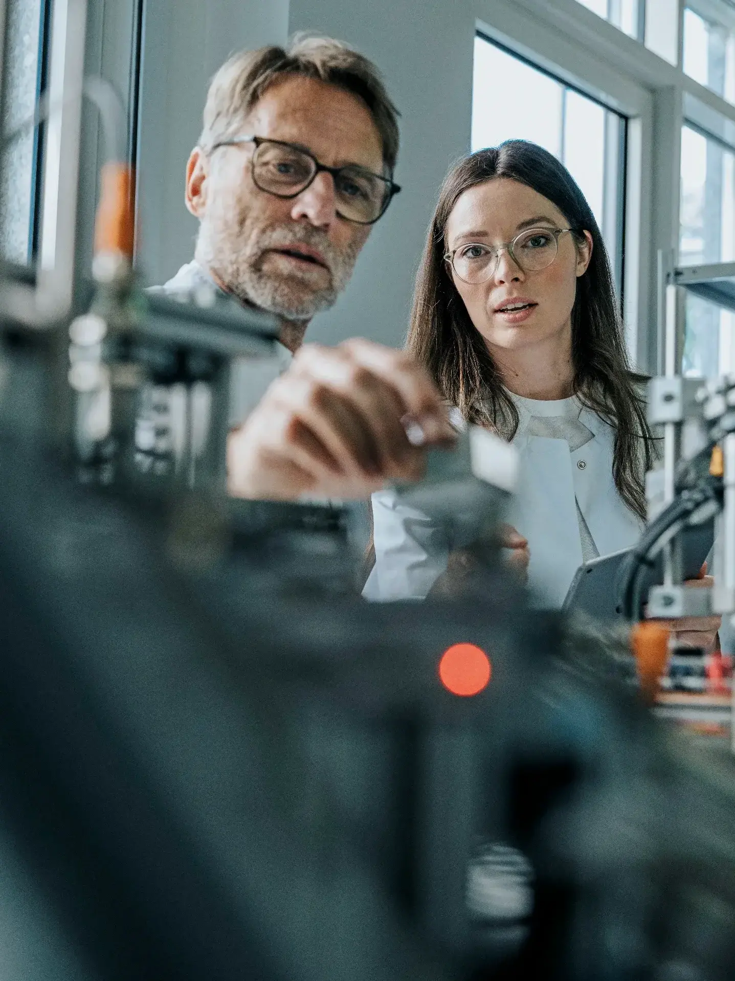 Male scientist with young woman examining machinery in laboratory