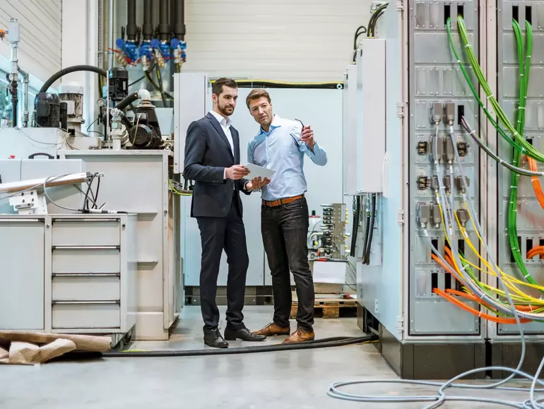 Two businessmen with tablet in factory