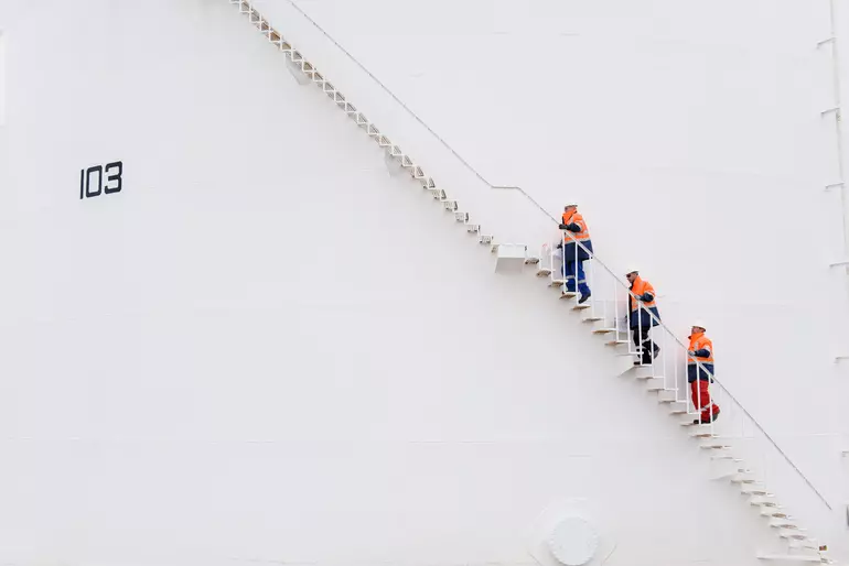 Technicians climbing fuel storage tank staircase