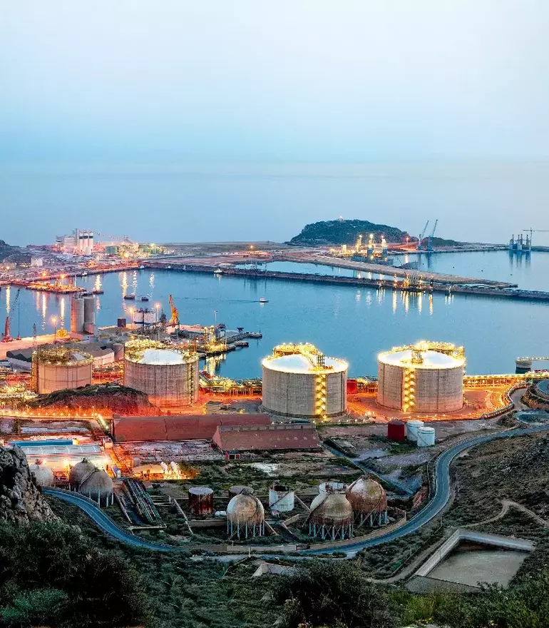 Petrochemische Anlage und Ölraffinerie am Meer bei Sonnenuntergang