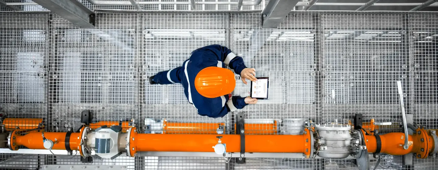 Man working at refinery oil production platform walking next to pipeline