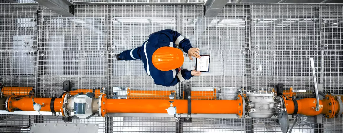 Man working at refinery oil production platform walking next to pipeline