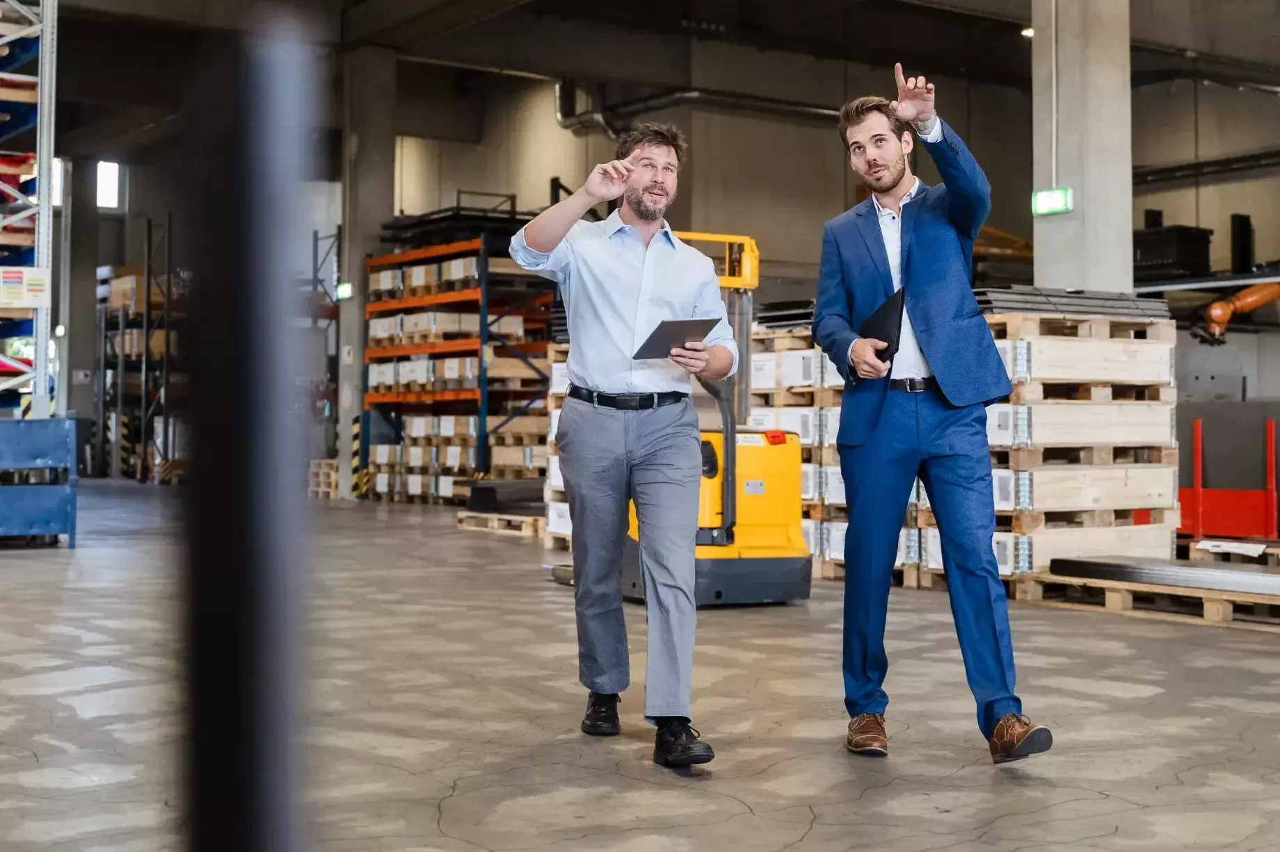 Businessman consulting at warehouse with colleague while walking at factory