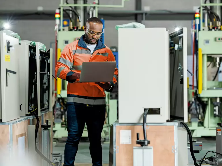 African engineer is examing and testing complex equipment by a laptop in a circuit cabinet