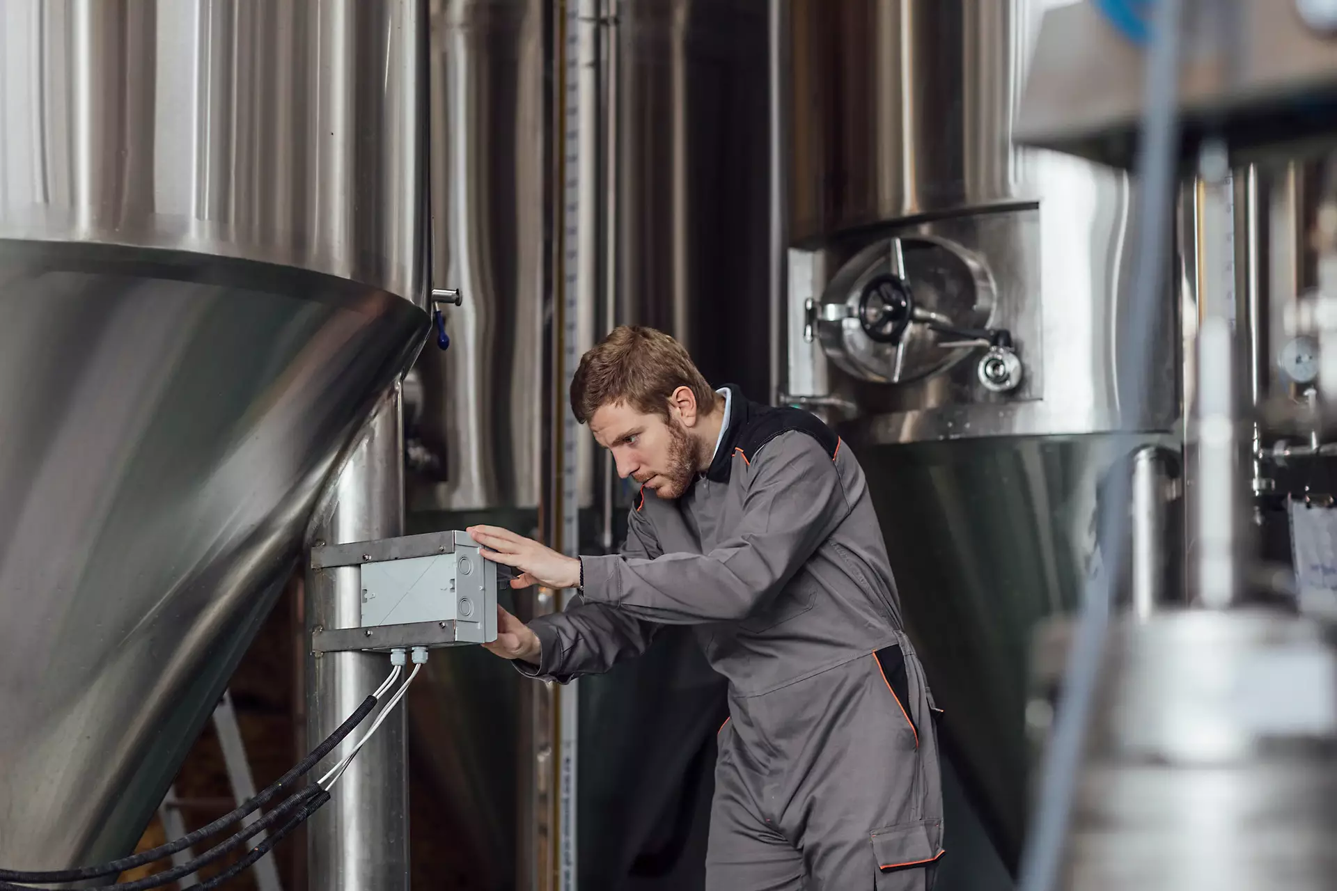 Distillery worker setting up human machine interface in factory
