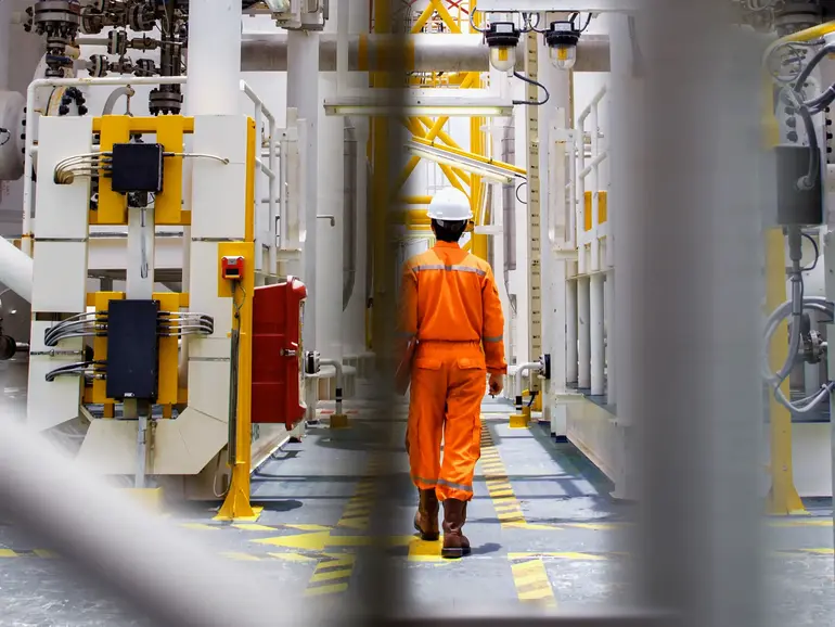 Man with helmet walking throug oil rig